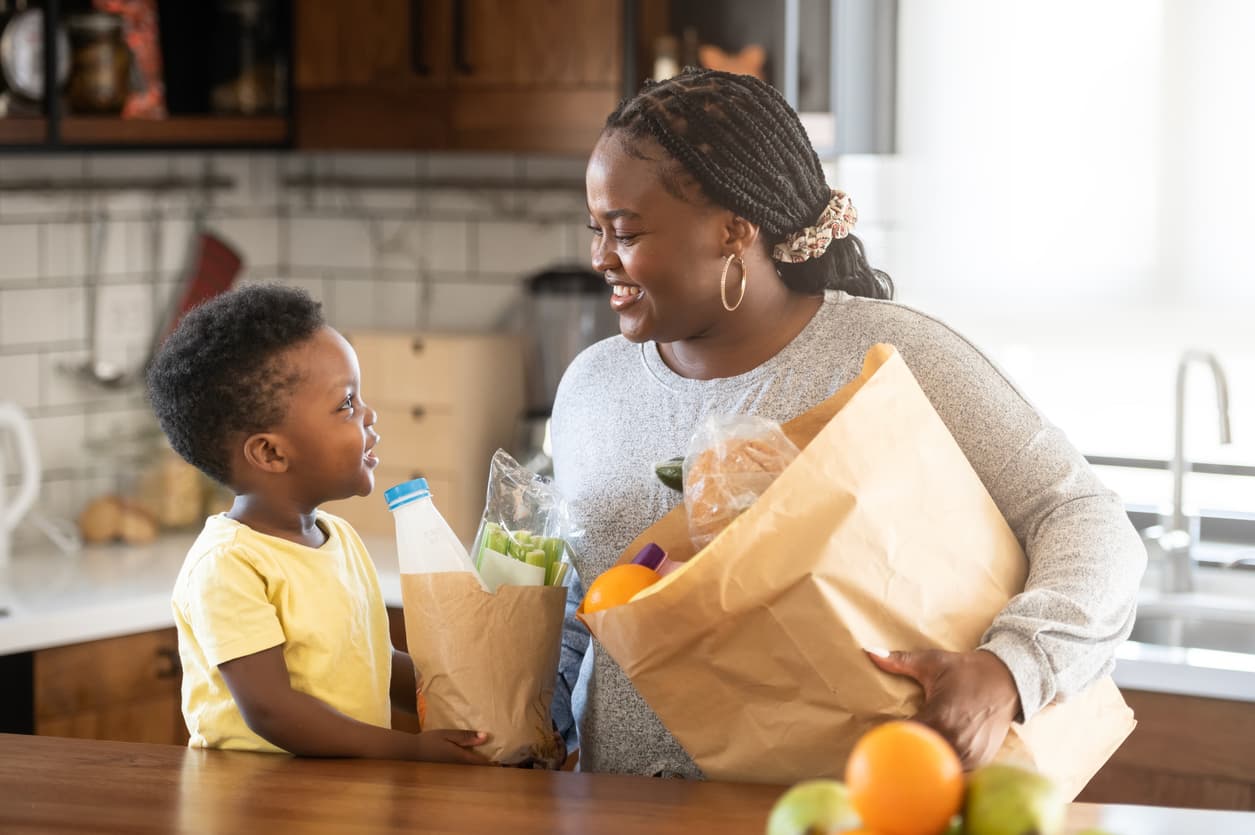 Happy mother and son unpacking fresh groceries together - iQpay digital food assistance benefits in action