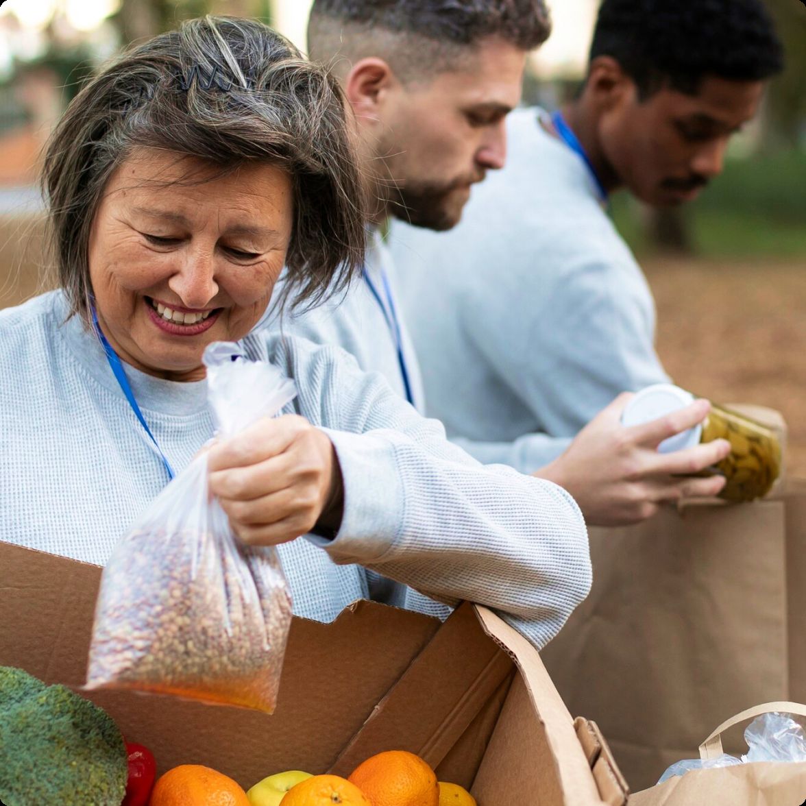 Volunteers packing bags of dry goods and produce into boxes at a food distribution.